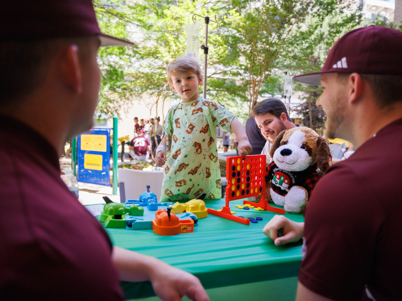 John Barron Barnes, a patient at Children's of Mississippi, plays a little Connect Four with his father, Brock, of Vicksburg, and MSU pitcher Tyler Barnes.
