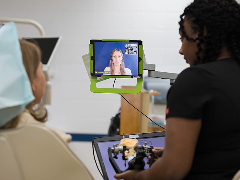 As School of Dentistry third-year student Kendra Clark, right, explains a dental procedure, a live video interpreter who speaks Portuguese prepares to translate Clark's English to patient and Brazil native Regina Wyatt.