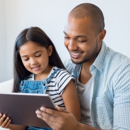 Father holds daughter while making an appointment online.