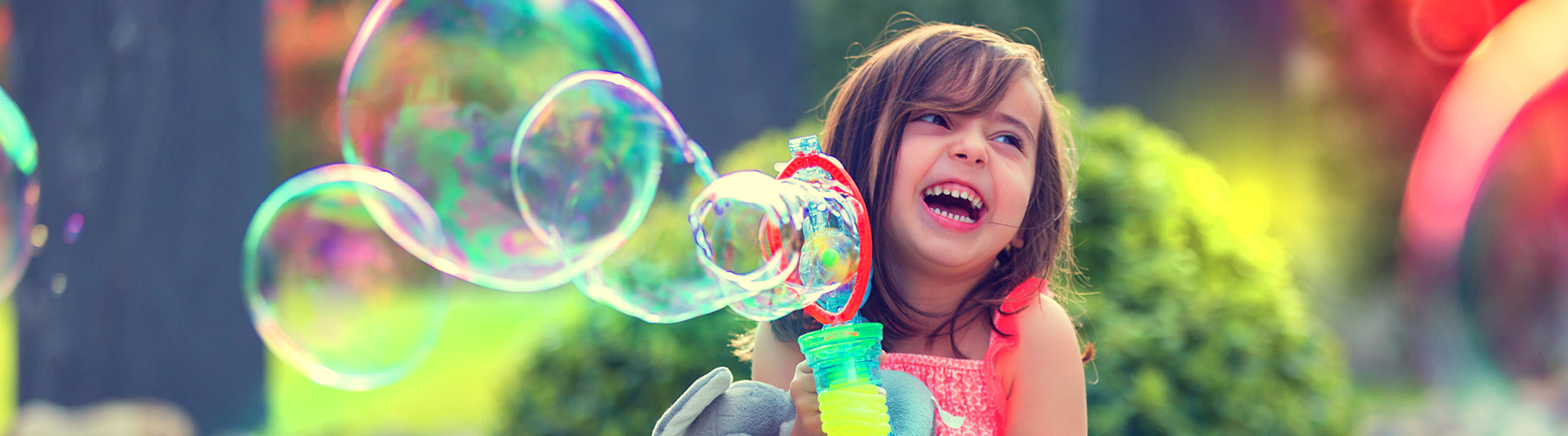 Little girl blowing bubbles outside