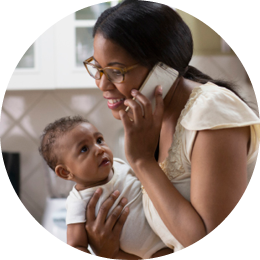 Mother holds child while making a phone call.