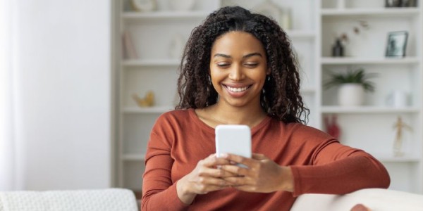 Woman smiles while looking at her phone.