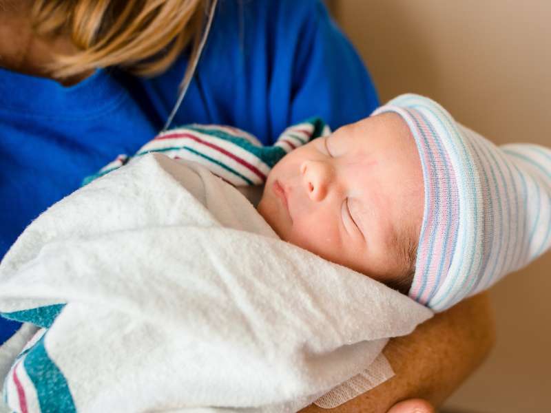 Health care professional holds newborn baby.