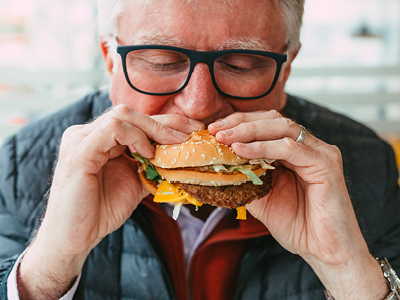 A man takes a large bite of a hamburger