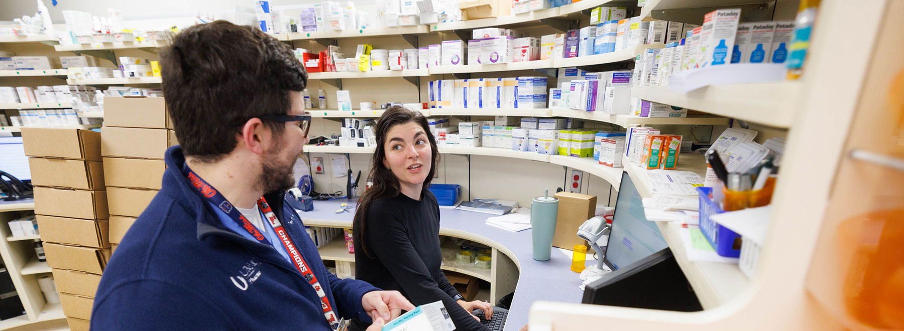 Trey Warnock and Mary Reagan Richardson talk while filling prescriptions at the pharmacy counter.