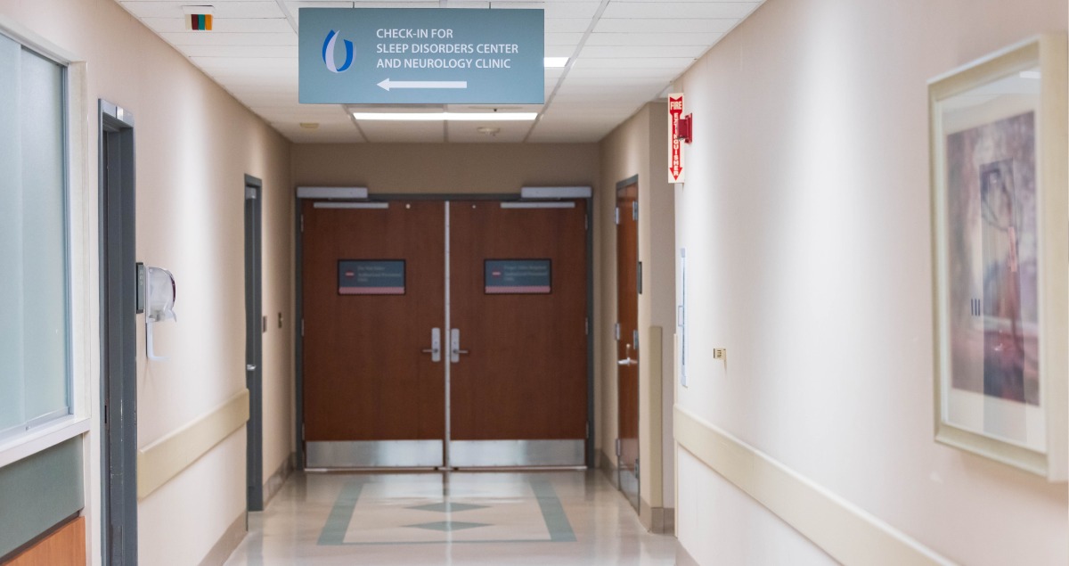 Hallway where patients check-in. Sign with an arrow points left to the correct door.