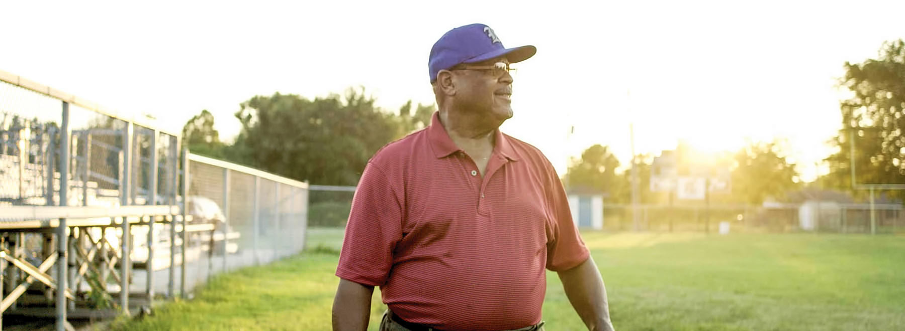 Man standing on football field in the morning light.