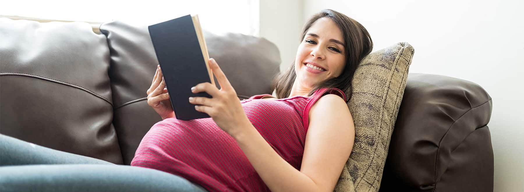 Pregnant woman reads while reclining on a couch