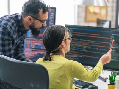 Two people studying computer screen as one points.