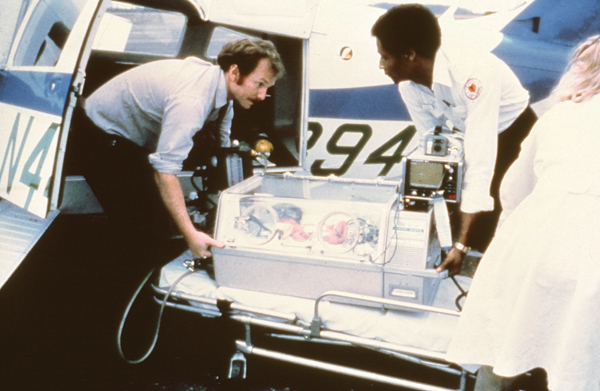 Dr. Phil Rhodes, left, professor emeritus of pediatrics and former division chief of newborn medicine, lifts an infant into a fixed-wing airplane with help from a Jackson Fire Department driver.