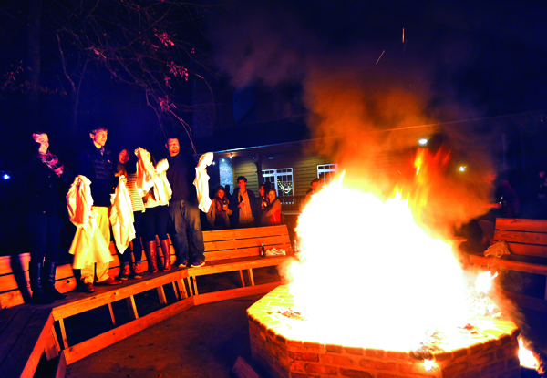 First-year medical students, from left, Kate Garner, Colton Lee, Cathy Chen, Kim Zachow and Brent Necaise join their fellow classmates in the coat-burning ritual, an annual rite of passage for M1s celebrating the end of Gross Anatomy by chucking their lab coats into a roaring fire. The ceremony was part of a semester-ending party held Dec. 12 at McClain Lodge in Rankin County. These five students, along with Rachel Sharp, worked together at the lab’s Table 25.