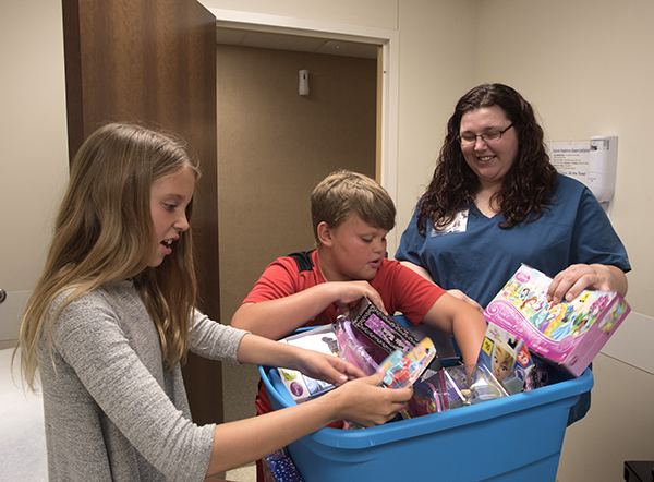 Amber Taylor, right, a family medicine nurse, helps twins Jordyn and Justice Burgemaster of Madison choose a toy from a box.