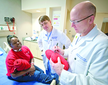  Dr. Simeone signs a heart shaped pillow for Mackey as Dr. Matthew deShazo looks on.