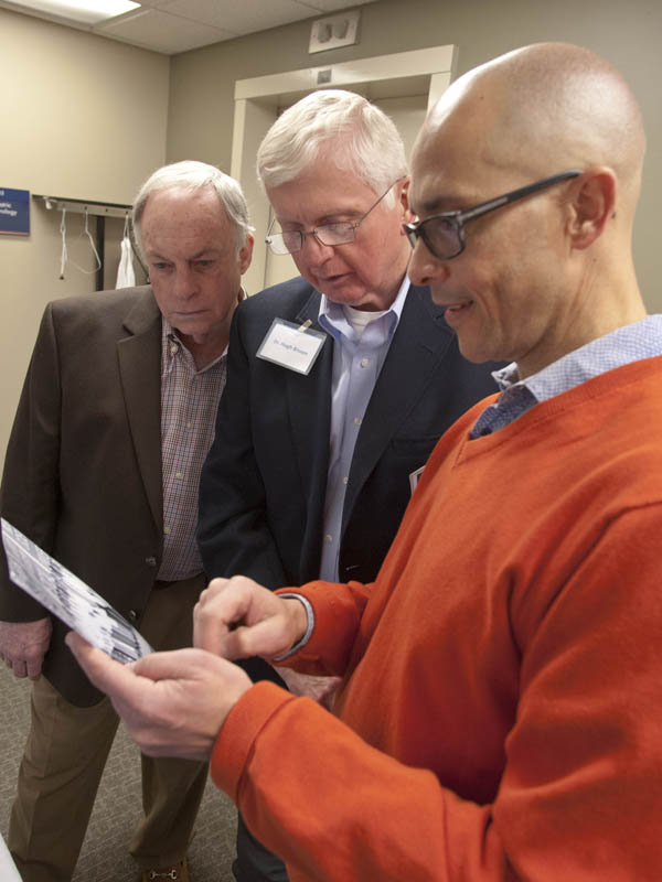 Dr. Mitch Massey, left, and Dr. Hugh Brown, center, look over a 1974 group portrait of the orthopedic surgery residents with Dr. George Russell.