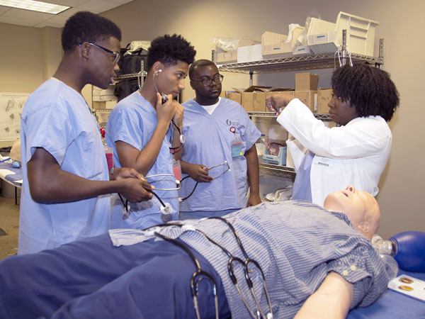 Danielle Parker, far right, Simulation Center coordinator, gives a lesson on ventilating a patient -- represented here by a mannequin -- to, from left, Murrah High School students Benjamin Knott and Myron Evans and Tevin Tillman, a University of Southern Mississippi student.