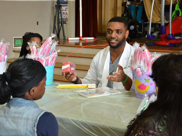 Chris Cathey, third-year dental student, instructs young students on how to properly brush their teeth.