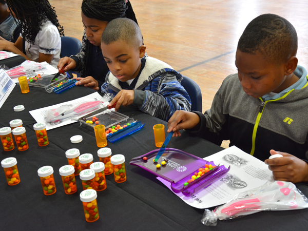 Zian Sims, right, Brian McCray and Desiree Strong learn the importance of pharmacy while participating in a mock pill-counting demonstration.