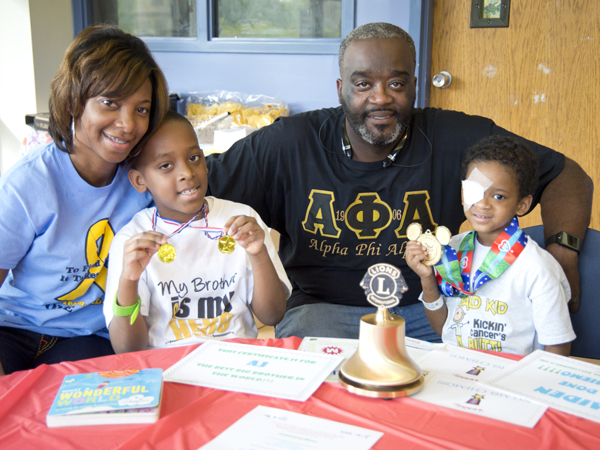 Deidre Johnson and Artis Johnson smile with sons Artis "AJ" and Aiden, right, during Aiden's ringing-out ceremony.