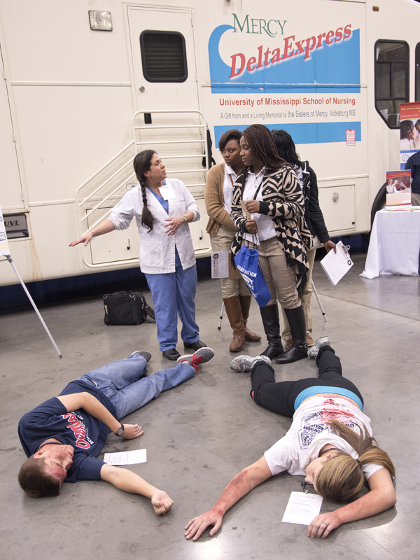 Eloise Lopez, an instructor in the SON simulation lab, explains the triage process to Murrah students De'Asia Williams, Madison Warren and Kiara Fuqua.