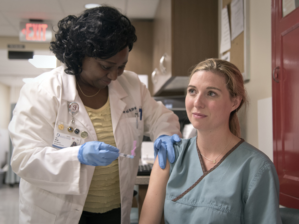 Joy Akanji, nurse manager of Student and Employee Health, gives a flu shot to Dr. Kayla Bryant, a pediatric dentistry resident.