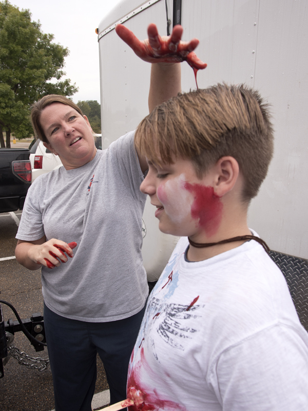Paula Vital, a nurse educator in UMMC's Center for Emergency Services, drips fake blood on the head of Northwest Rankin Middle School student Chris Russell