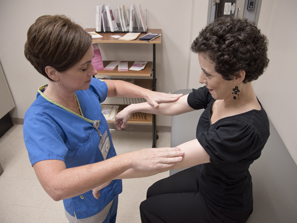 Patients who undergo treatment for breast cancer can suffer from loss of strength and range of motion. Vining, left, performs manual muscle testing reassessment of shoulder flexion for patient Sara Harvey Roberts.