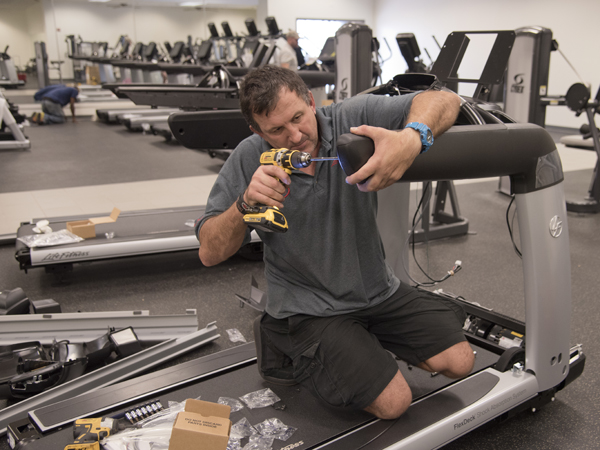 Nihad Lesnjanin, an employee of equipment manufacturer Life Fitness. puts together a treadmill for installation at the University Wellness Center in downtown Jackson.