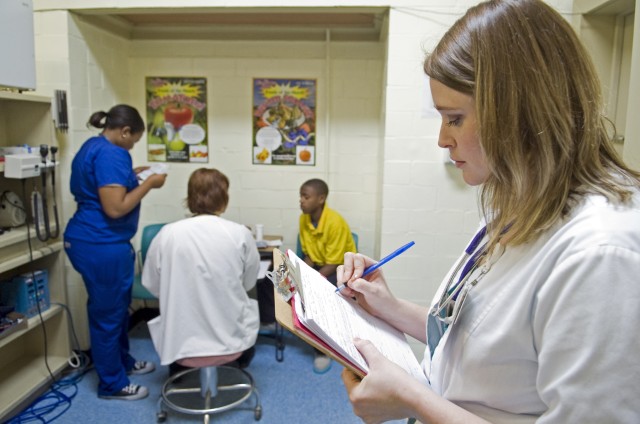 Kayla Logan (right), RN, charts while second-year medical student Kristen Dent (left) helps nurse practitioner Kathy Rhodes examine a South Delta Middle School student inside the school’s clinic. The new grant-funded program will start in two schools in January with plans to expand to additional school-based clinics, including South Delta, within three years.