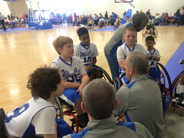 Morgan, back center, listens to his coach during an pre-game huddle of the Mississippi Wheelcats.