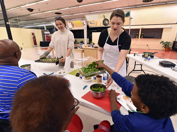 Bidwell, standing right, provides healthy food and nutrition information at the Midtown teaching kitchen