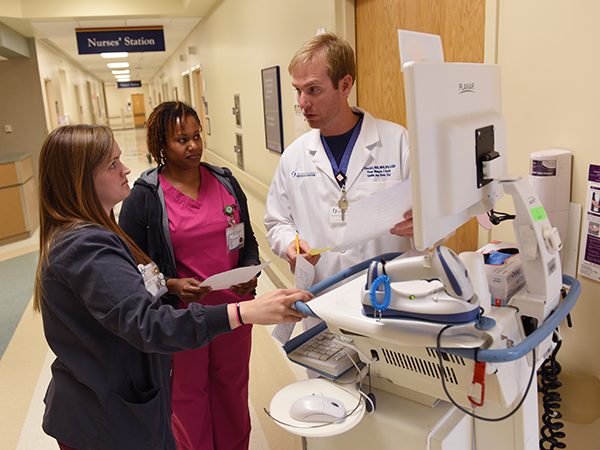 John Michael Churchill, nurse manager of 3 South, talks with RN's Meagan Wiley, left, and Youlanda Jones about a patient.
