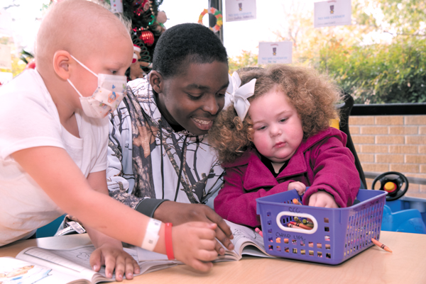 Freddie Green Jr., center, spends time with Bentley Broussard, left, and his sister Brooklyn at the Children’s Cancer Clinic.