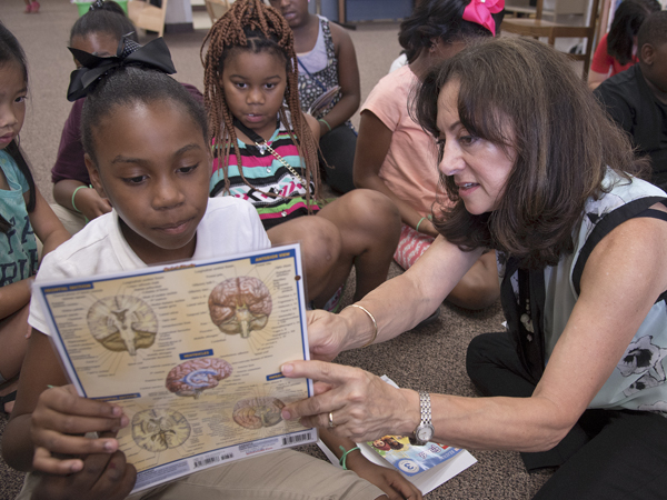 Buttross gives Greenwood Summer Food Rocks attendees Jalysia Summerville, left, and Braelyn Johnson a lesson on how the brain works.