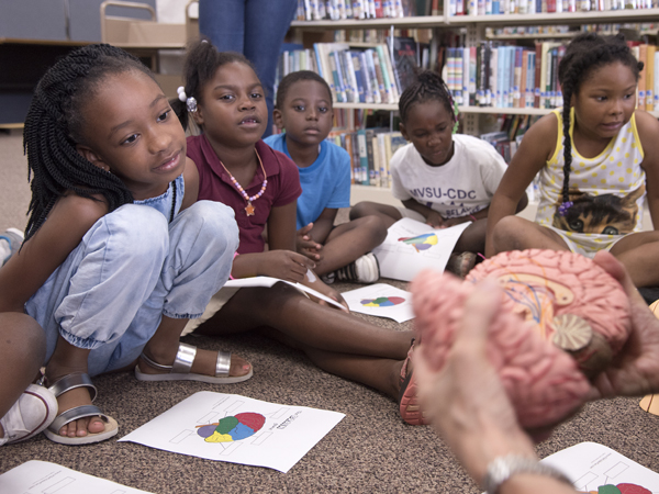 Students in Summer Food Rocks get a look at a model of the brain.