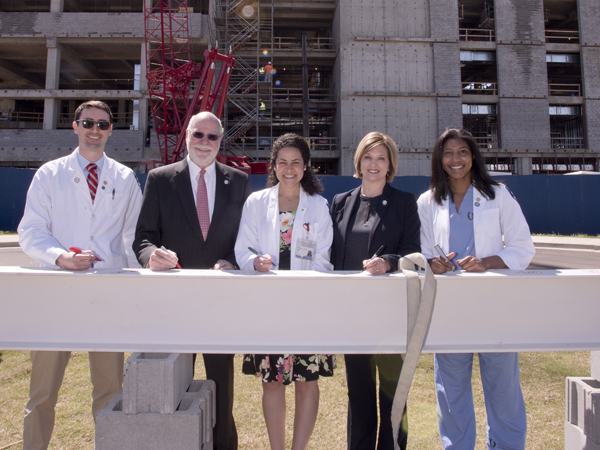 Among those who signed the construction beam during Monday's topping-out ceremony are, from left, second-year medical student John Lippincott; former UMMC vice chancellor Dr. James Keeton, distinguished professor and advisor to the vice chancellor; fourth-year medical student Sara Ali; Dr. LouAnn Woodward, vice chancellor for health affairs and dean of the School of Medicine; and first-year medical student Michelle Wheeler.