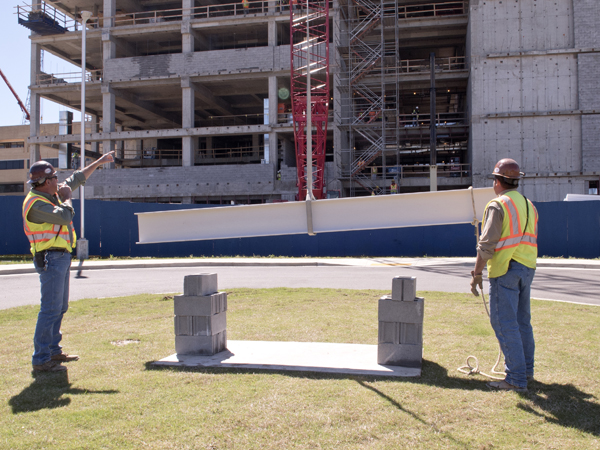 Members of the construction crew direct the lifting of a structural beam to the top of the new School of Medicine building during Monday's ceremony marking a construction milestone.