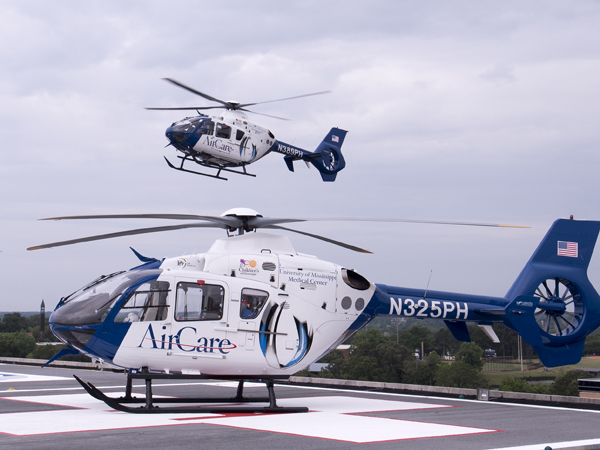 AirCare 3 sits on the helipad atop UMMC's Conerly Critical Care Hospital as AirCare 2 departs.