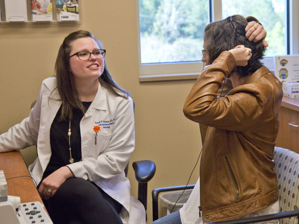 Dr. Vicki Gonzalez, left, observes as Edmonson demonstrates positioning her cochlear implant.