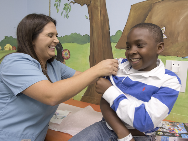 Christian Quarles, an oncology nurse at the Children's Cancer Clinic, gets patient Derrick James, 9, of Byram ready for his flu shot.