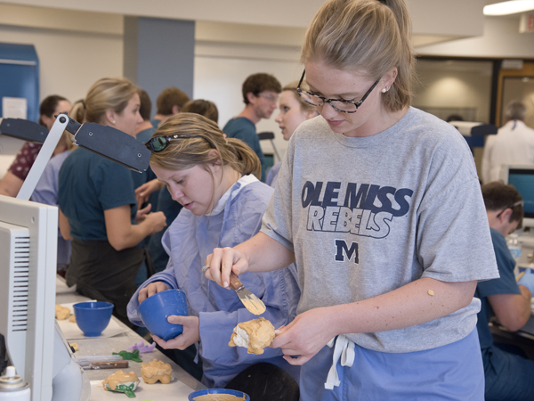 School of Dentistry students Molly Edmondson and Jennybeth Hendrick work on denture forms in a crowded laboratory.