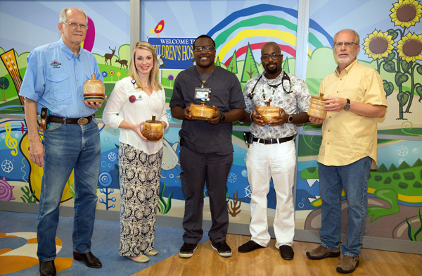 Magnolia Woodturners Gerald Lawrence, left, and Michael Frazier, right, show some of their bowls for Beads of Courage. Receiving the donation are, from second from left, social worker Melissa Underwood, respiratory therapist Jacolby Anderson and Dr. David Josey, assistant director of the CF center at Batson Children's Hospital.