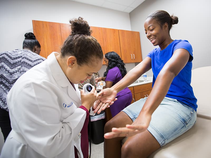 Dr. Jasmine Hollinger, assistant professor of dermatology, checks the skin of Belzoni resident Twyla Courts during a free health screening at the Community Care Clinic.