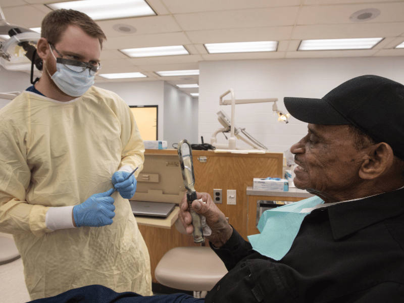 Glover, left, makes minor adjustments to Sutton's dentures during a fitting appointment on Wednesday.