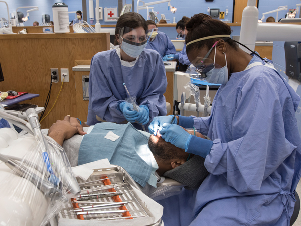 Maggie Peebles and Labrea' Othello, dental hygiene juniors, provide patient Joshua Smith of Jackson with a cleaning during Dental Mission Week