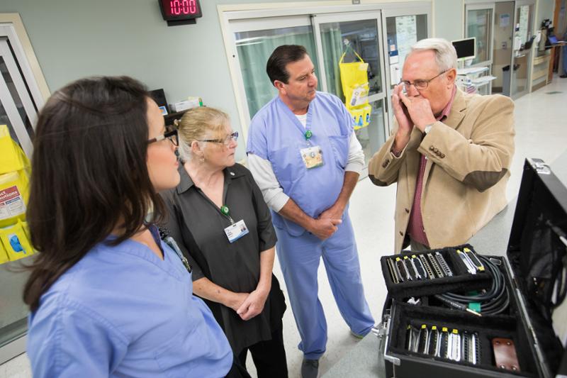 Former patient David Bowman, right, plays harmonica for CICU staff members, from left, Registered Nurse Presly Lowry, housekeeper Cynthia Gonzalez and Nurse Manager Don Horn during a return visit to the CICU.