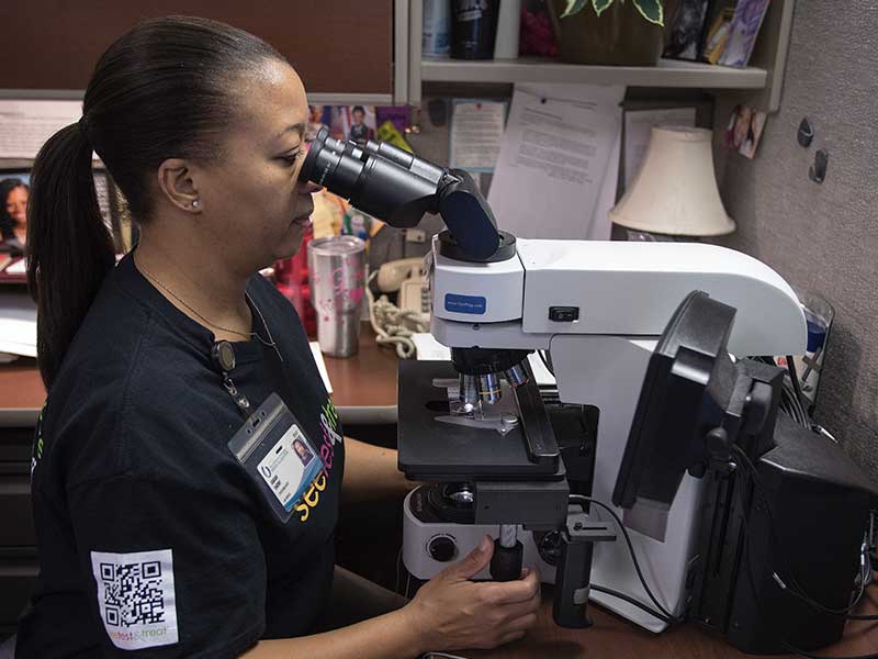 Sarah Short, cytotechnologist, reviews Pap test slides during the Jan. 28, 2017 See, Test & Treat event. The pathology team returns this year so women can receive readings the same day.