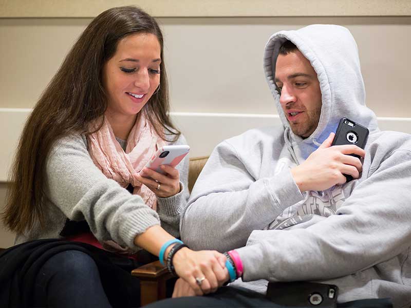 Eppes snaps a photo of the couple's hands and wrist bands to make a social media post while waiting for Sands to be called back for his recent cancer surgery.