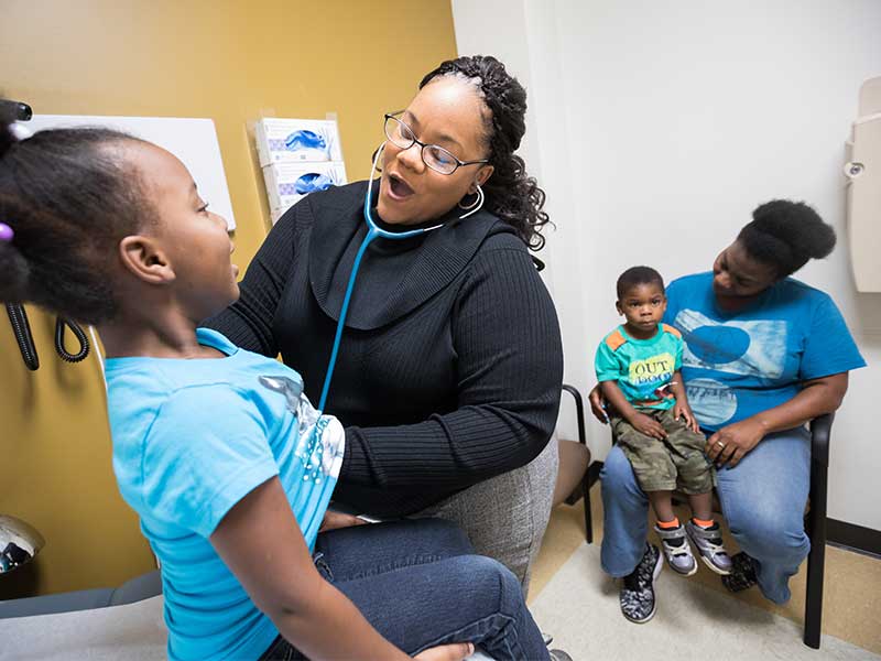 Moore entertains Madysen Palmer, 5, while checking out her breathing; her brother Jarvis Lenson, 2, sitting with their mother Porshia Palmer, awaits his turn.