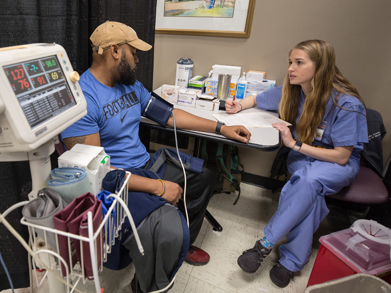 In medical triage, Lydia Nunes, a first-year medical student, takes the medical history of Treance Hobbs, of Pearl.