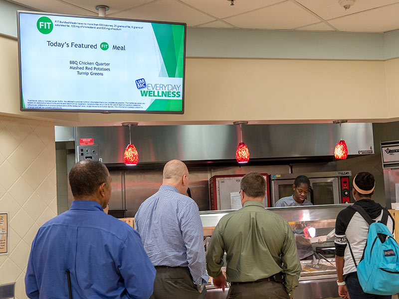 Students and employees line up at the cafeteria's hot entree bar, where daily choices include a featured "FIT" meal meeting Everyday Wellness requirements for good nutrition.